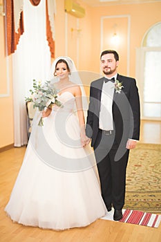 Beauty bride and handsome groom are wearing rings each other. Wedding couple on the marriage ceremony.