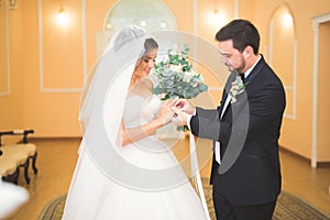 Beauty bride and handsome groom are wearing rings each other. Wedding couple on the marriage ceremony.