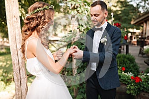 Beauty bride and handsome groom are wearing rings each other. Wedding couple on the marriage ceremony. Beautiful model girl in whi