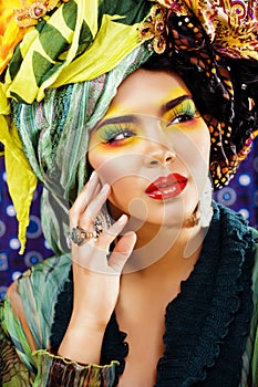 Beauty bright woman with creative make up, many shawls on head like cubian, ethno look closeup