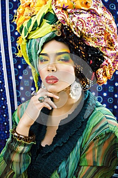 Beauty bright woman with creative make up, many shawls on head like cubian, ethno look closeup