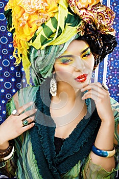 Beauty bright woman with creative make up, many shawls on head like cubian, ethno look closeup