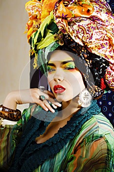 Beauty bright woman with creative make up, many shawls on head like cubian, ethno look closeup