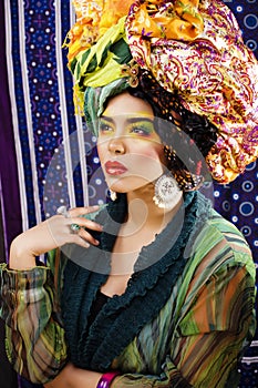 Beauty bright woman with creative make up, many shawls on head like cubian, ethno look closeup