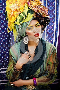 Beauty bright woman with creative make up, many shawls on head like cubian, ethno look closeup