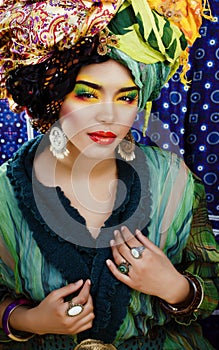 Beauty bright woman with creative make up, many shawls on head like cubian, ethno look closeup