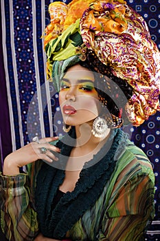 Beauty bright woman with creative make up, many shawls on head like cubian, ethno look closeup