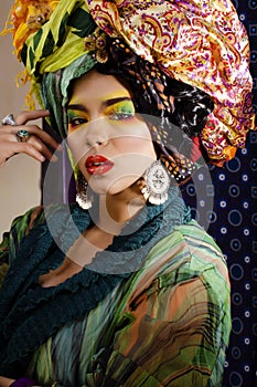 Beauty bright woman with creative make up, many shawls on head like cubian, ethno look closeup