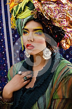 beauty bright woman with creative make up, many shawls on head like cubian, ethno look closeup