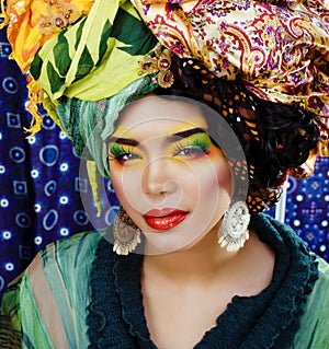 beauty bright woman with creative make up, many shawls on head like cubian, ethno look closeup