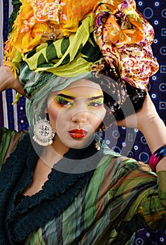 beauty bright woman with creative make up, many shawls on head like cubian, ethno look closeup