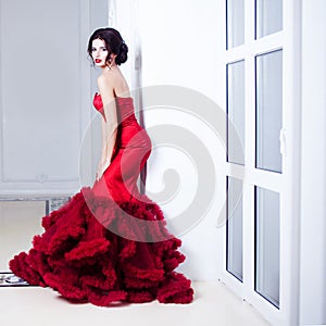 Beauty Brunette model woman in evening red dress. Beautiful fashion luxury makeup and hairstyle. Seductive silhouette. A girl stan