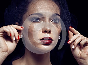 Beauty brunette woman under black veil with red manicure close up, grieving widow, halloween makeup