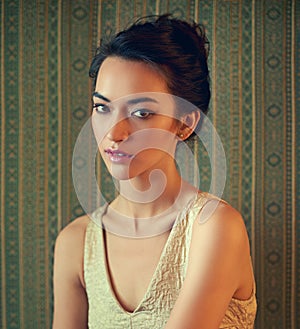 Beauty that captures the attention. Portrait of a beautiful young woman dressed elegantly in a wallpapered room.