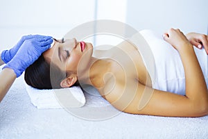 Beauty and Care. Beautiful Young Girl Lying On Massage Tables In Spa Salon. Facial Massage. Hands of a Cosmetologist