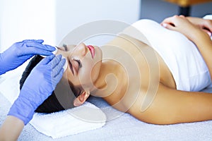 Beauty and Care. Beautiful Young Girl Lying On Massage Tables In Spa Salon. Facial Massage. Hands of a Cosmetologist