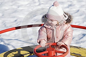 Beauty child . happy child on a swing on a sunny spring day. Happy baby girl in a pink hat and scarf laughs