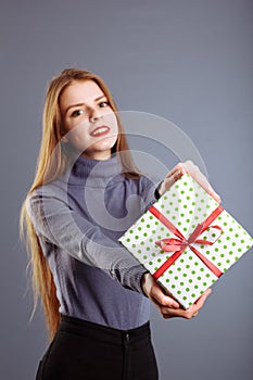 Beauty Christmas fashion model girl holding Xmas gift box. Beautiful lady, Long straight flying hair, red santa hat