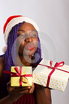 Beauty Christmas fashion model girl holding Xmas gift box. Beautiful lady, Long straight flying hair, red santa hat, holding gift