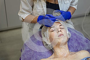 Beauty Clinic.woman gets a professional facial procedure. Beautician makes massage on a woman`s face. face renewal