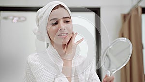 In a beauty clinic, a woman looking in a mirror admires her face after the surgery