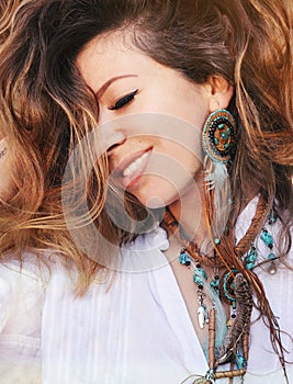 Beauty close up fashion smiling woman portrait with handmade necklace and earrings made with beads, leather and feathers, boho chi photo