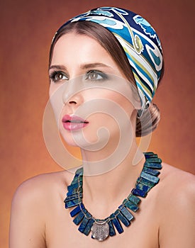 Beauty closeup portrait of beautiful young woman in a headscarf. Necklace on her neck