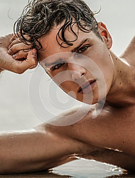 Beauty closeup portrait of handsome young man. Boy looking at the camera, relaxing on the beach