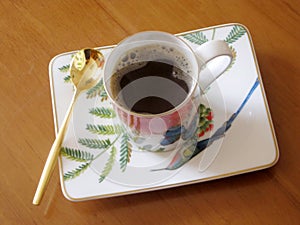 Beauty coffeecup standing on wooden table with dark tasty coffee