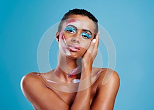 Beauty comes in many colours. Studio portrait of a beautiful young woman covered in face paint posing against a blue