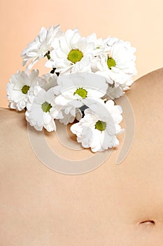 Beauty concept: close up on a caucasian girl`s bellybutton with a bouquet of white flowers photo