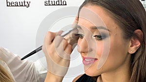 Beauty concept. Makeup artist doing face make up to young woman