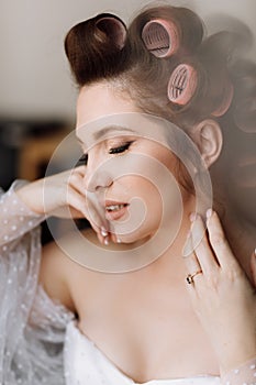 beauty concept. portrait of a beautiful young showy brunette woman with bright pin-up make-up in pink curlers. Studio