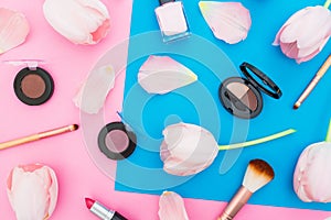 Beauty concept with spring flowers and cosmetics on blue and pink background. Top view. Flat lay. Spring time