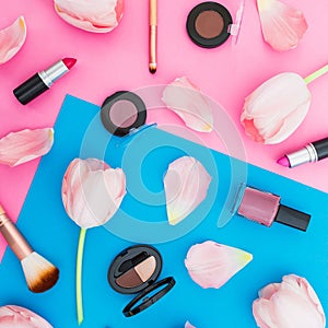 Beauty concept with tulips flowers and cosmetics on blue and pink background. Top view. Flat lay. Spring time