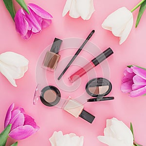 Beauty concept with tulips flowers and cosmetics on pink background. Top view. Flat lay. Home feminine desk.