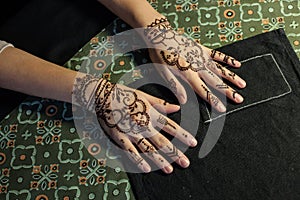 Beauty concept - two hand of girl being decorated with henna mehendi Tattoo. Close-up, overhead view