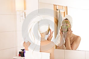 Beauty concept. The woman applies green organic face mask in the bathroom