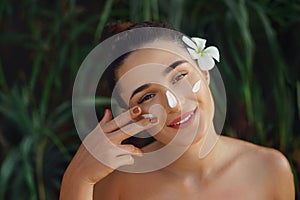 Beauty Concept. Woman Applying  Cosmetics Cream, Spreads it on her face to moisturize her skin and Smiling.  Beauty Face