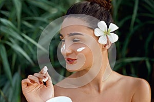 Beauty Concept. woman holds a moisturizer in her hand and spreads it on her face to moisturize her skin and wrinkle from impuritie