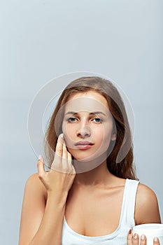 Beauty Concept. woman holds a moisturizer in her hand and spreads it on her face  to moisturize her skin