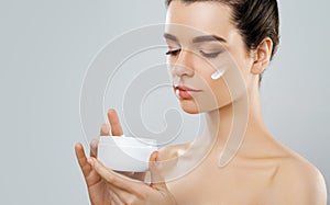 Beauty Concept. woman holds a moisturizer in her hand and spreads it on her face to moisturize her skin