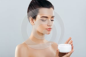 Beauty Concept. woman holds a moisturizer in her hand and spreads it on her face to moisturize her skin