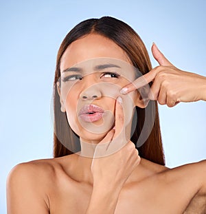 Beauty, cosmetics and woman squeeze pimple, skincare and girl with breakout against blue studio background. Female, lady