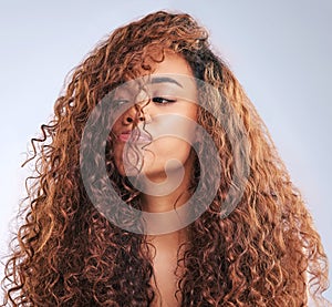Beauty, curly or haircare and annoyed woman in studio on gray background with moody expression. Hair, salon and unhappy