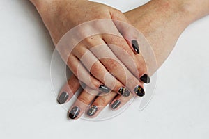 beauty delicate coffee manicure with gold sparkles with gel varnish on a white wall background