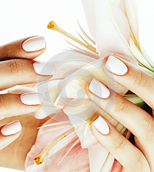 Beauty delicate hands with manicure holding flower lily close up