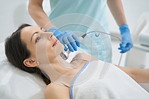 Beauty expert using RF-therapy on female neck