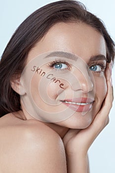 Beauty Face. Beautiful Woman Close Up Portrait. Smiling Model With Perfect Skin And Words â€œSkin Careâ€ Written On Cheekbone.