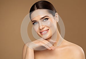 Beauty Face Care. Smiling Woman with natural Make up touching Facial Healthy Skin over Beige. Facelift Massage and Spa Cosmetology
